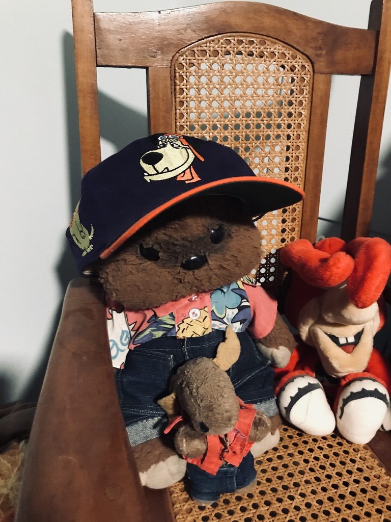 Wicket ewok stuffed animal wearing a Muttley ball cap sitting in a child's rocking chair