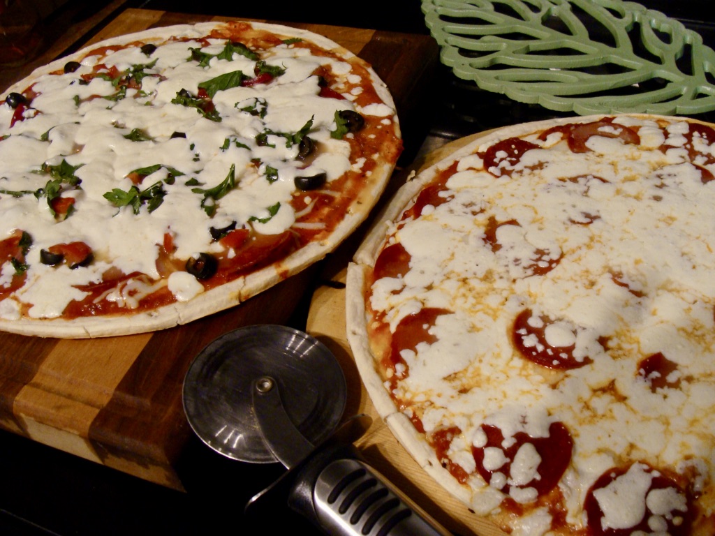 two fresh baked pizzas on cutting boards