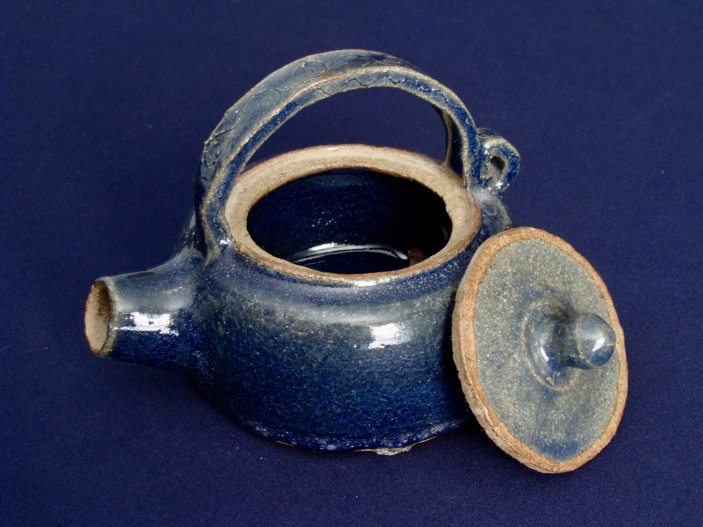a blue clay teapot on a blue backdrop