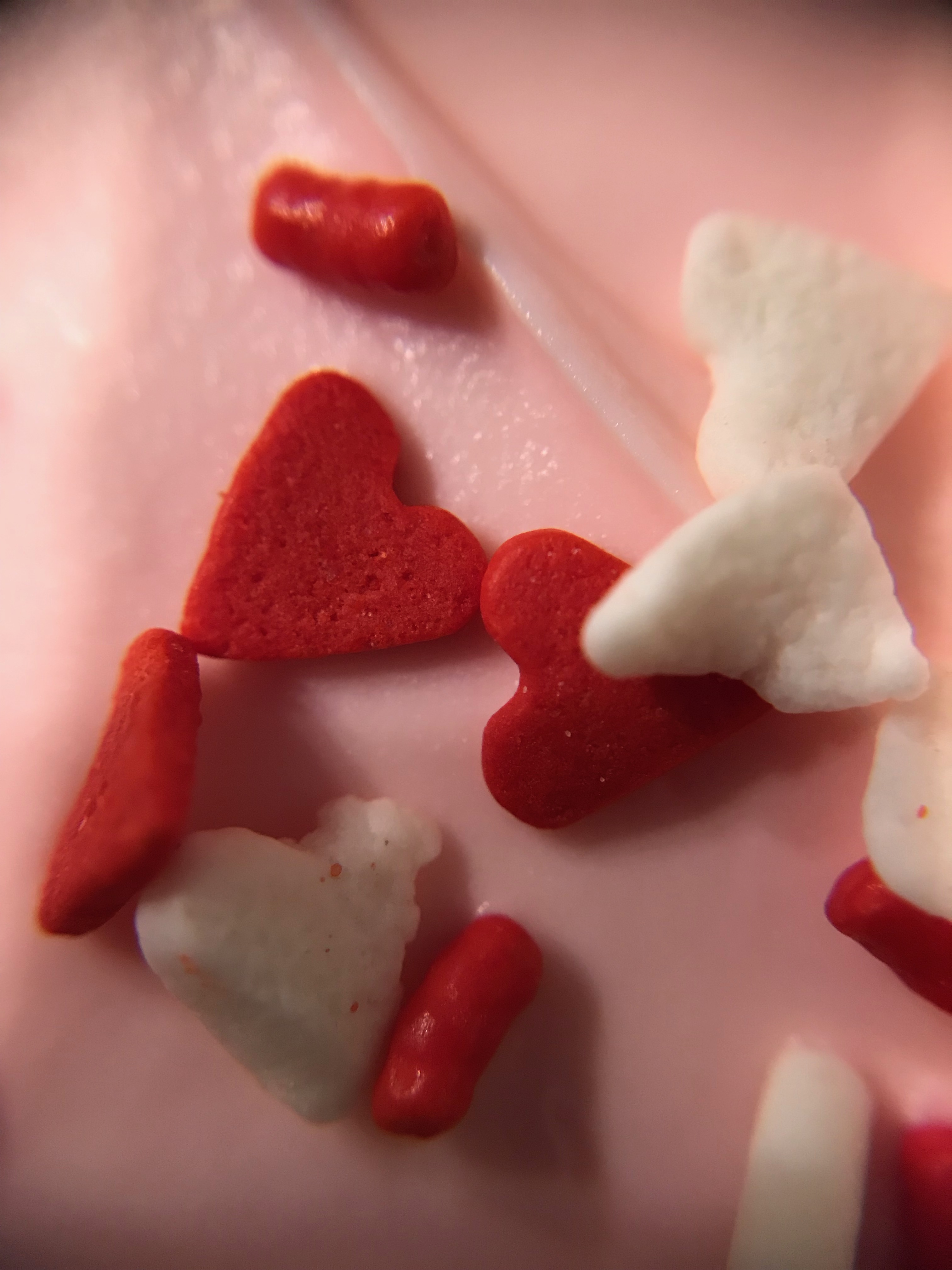 Close up of red and white heart sprinkles on icing