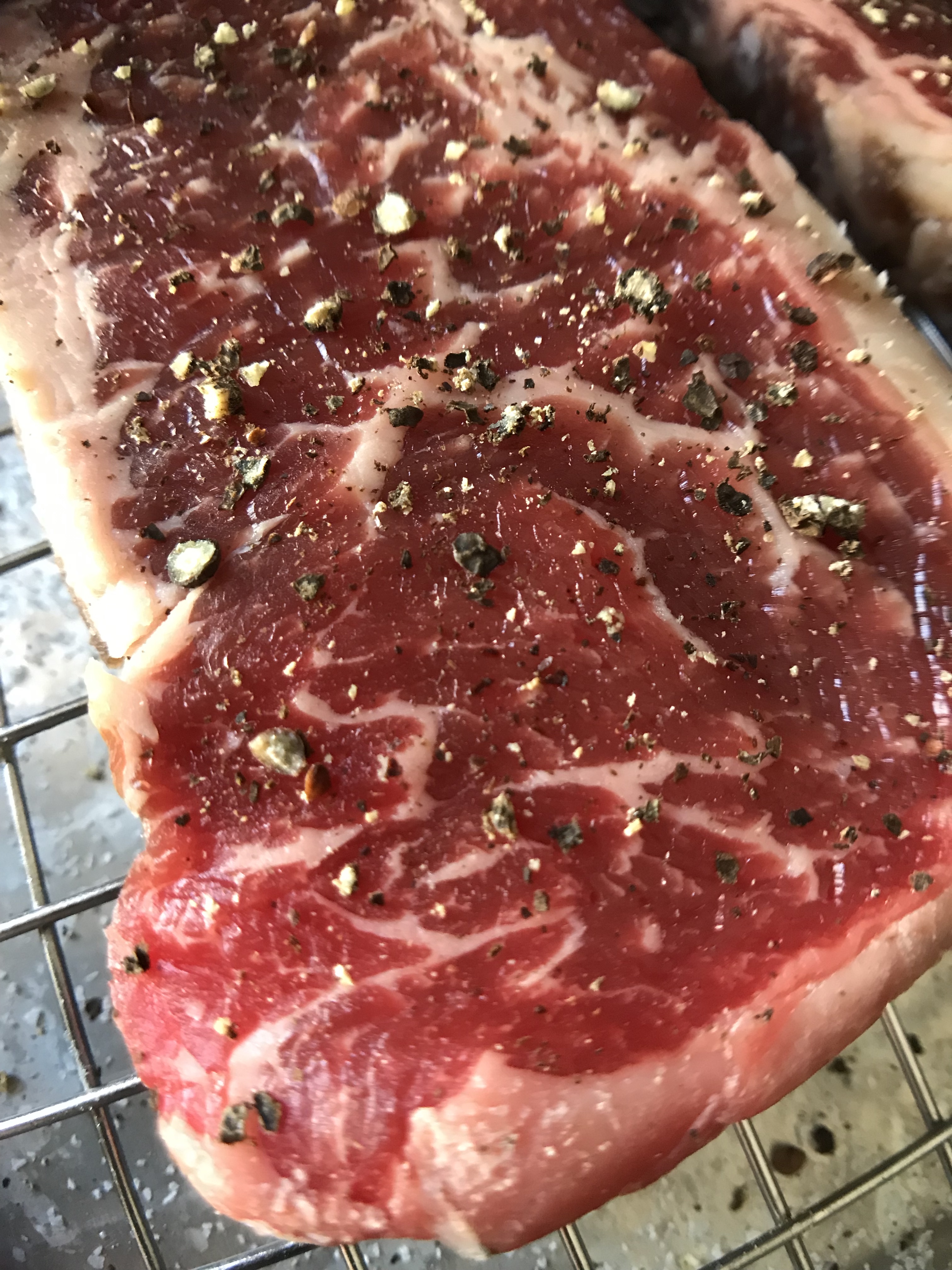 raw steak covered in pepper
