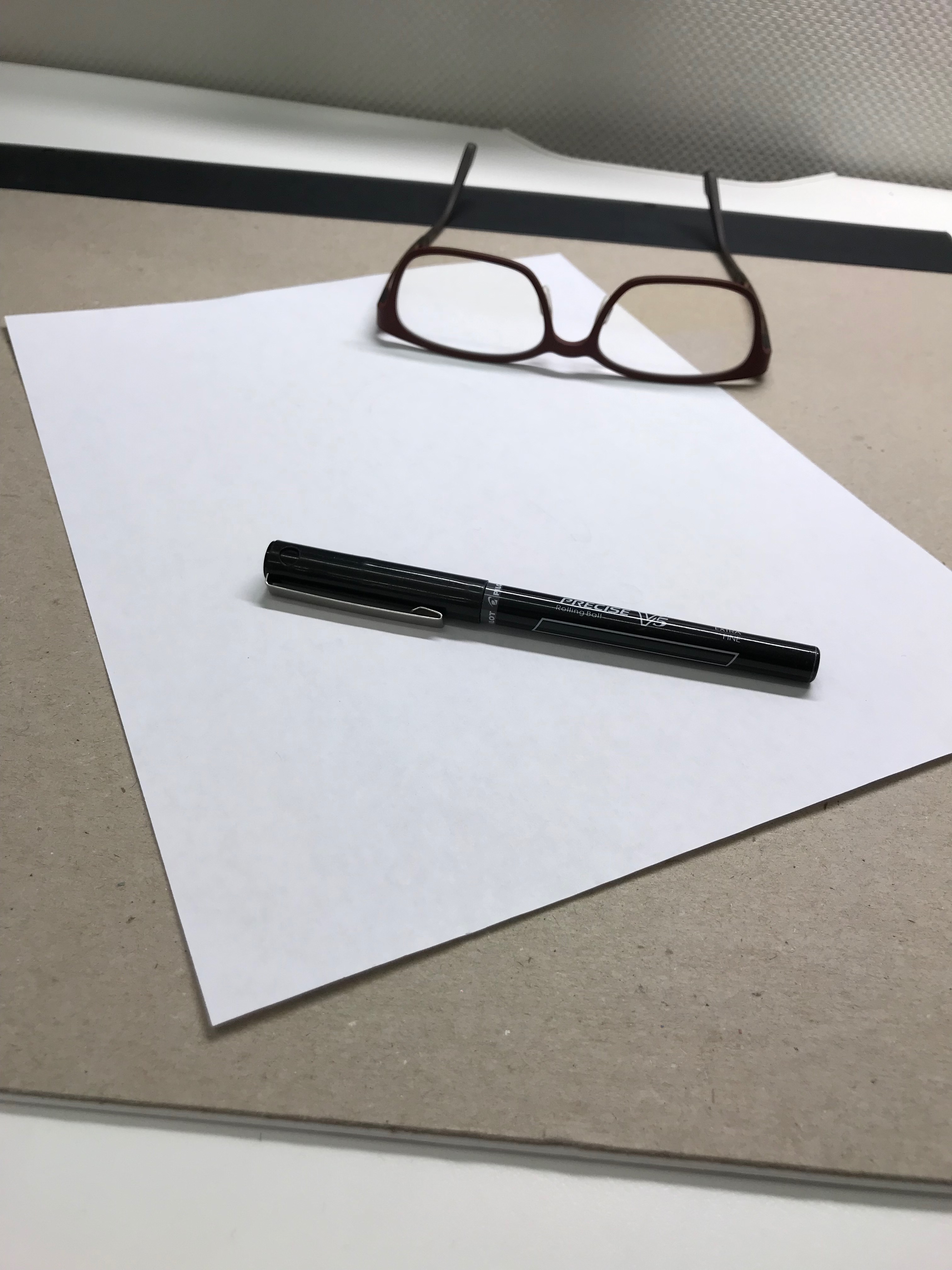 Piece of paper, pen and glasses on a desk