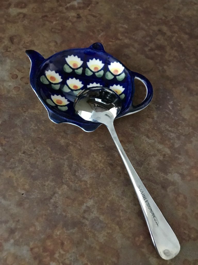 A little spoon upside down in a teapot shaped spoon rest