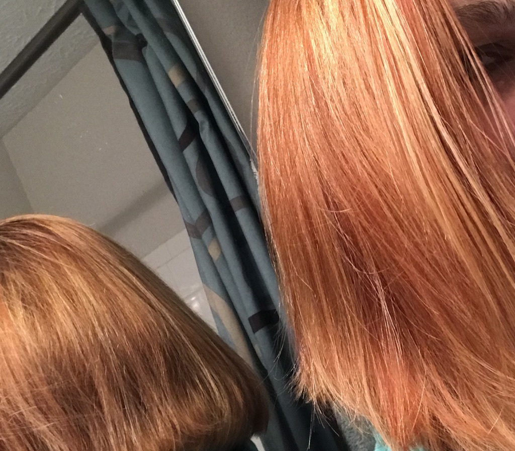 A head of red and blond hair with back of head reflecting in mirror