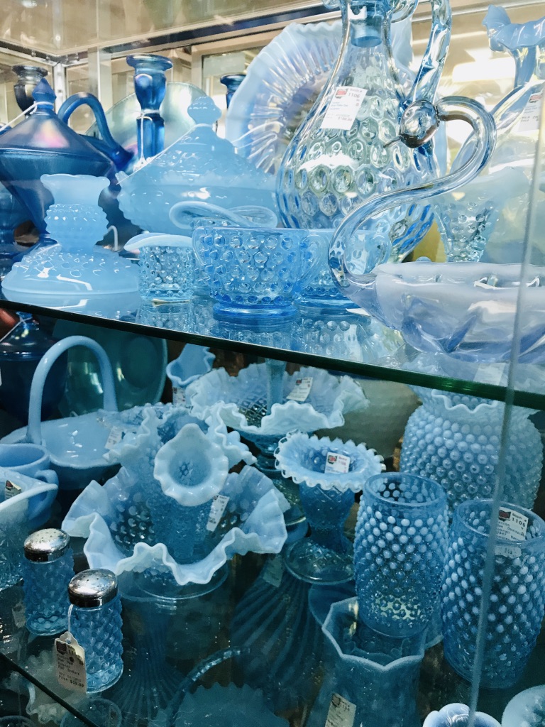 Glass case filled with antique blue glass dishes.