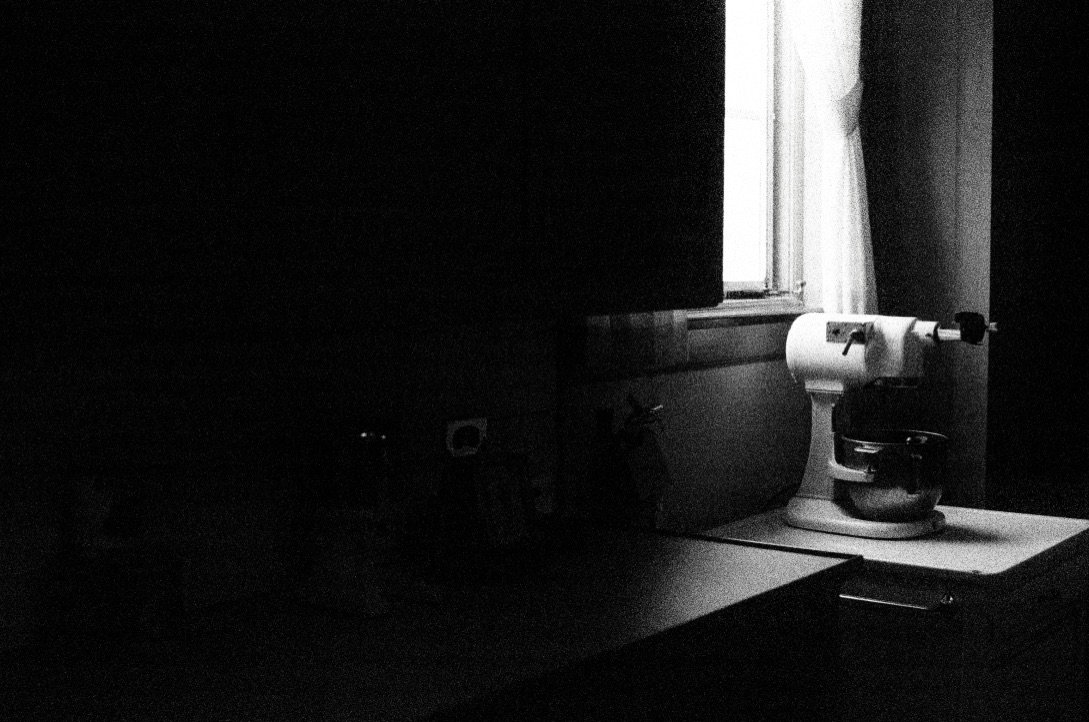 window lighting an old mixer rest of kitchen is dark