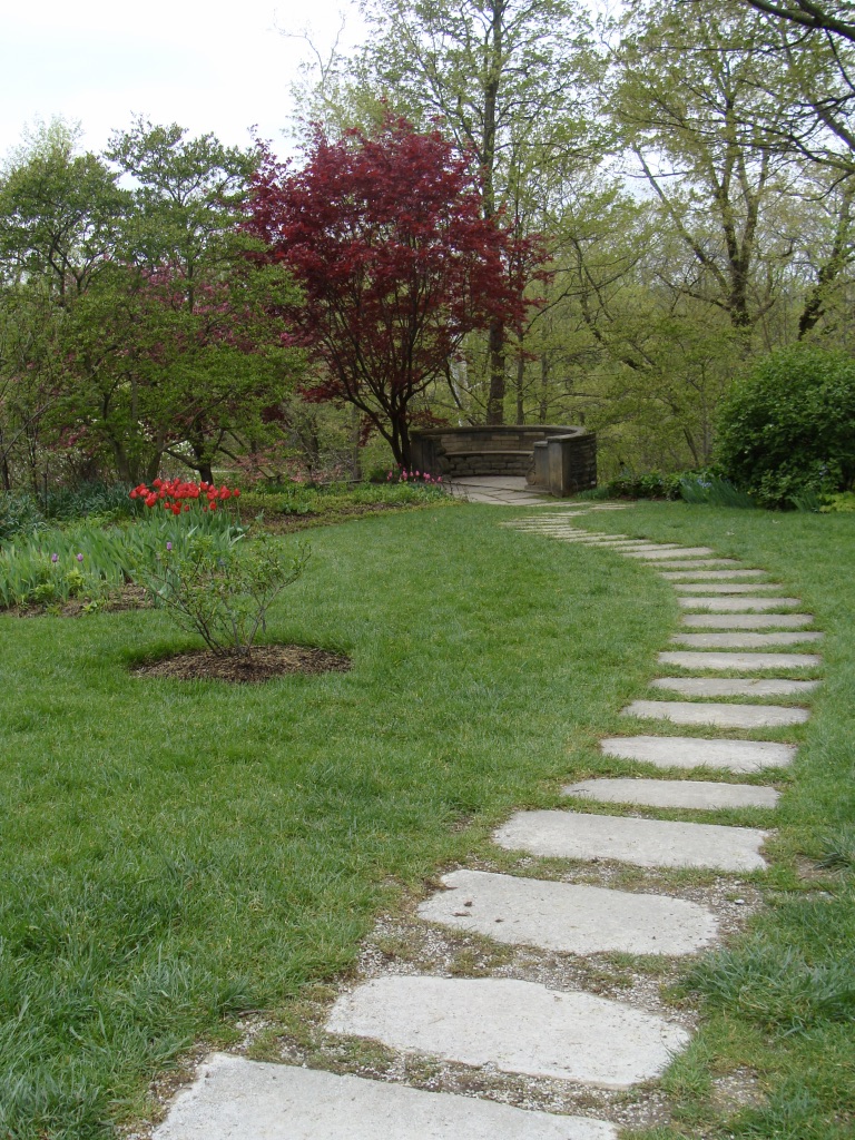 Stone slab winding walkway in a garden with flowers.