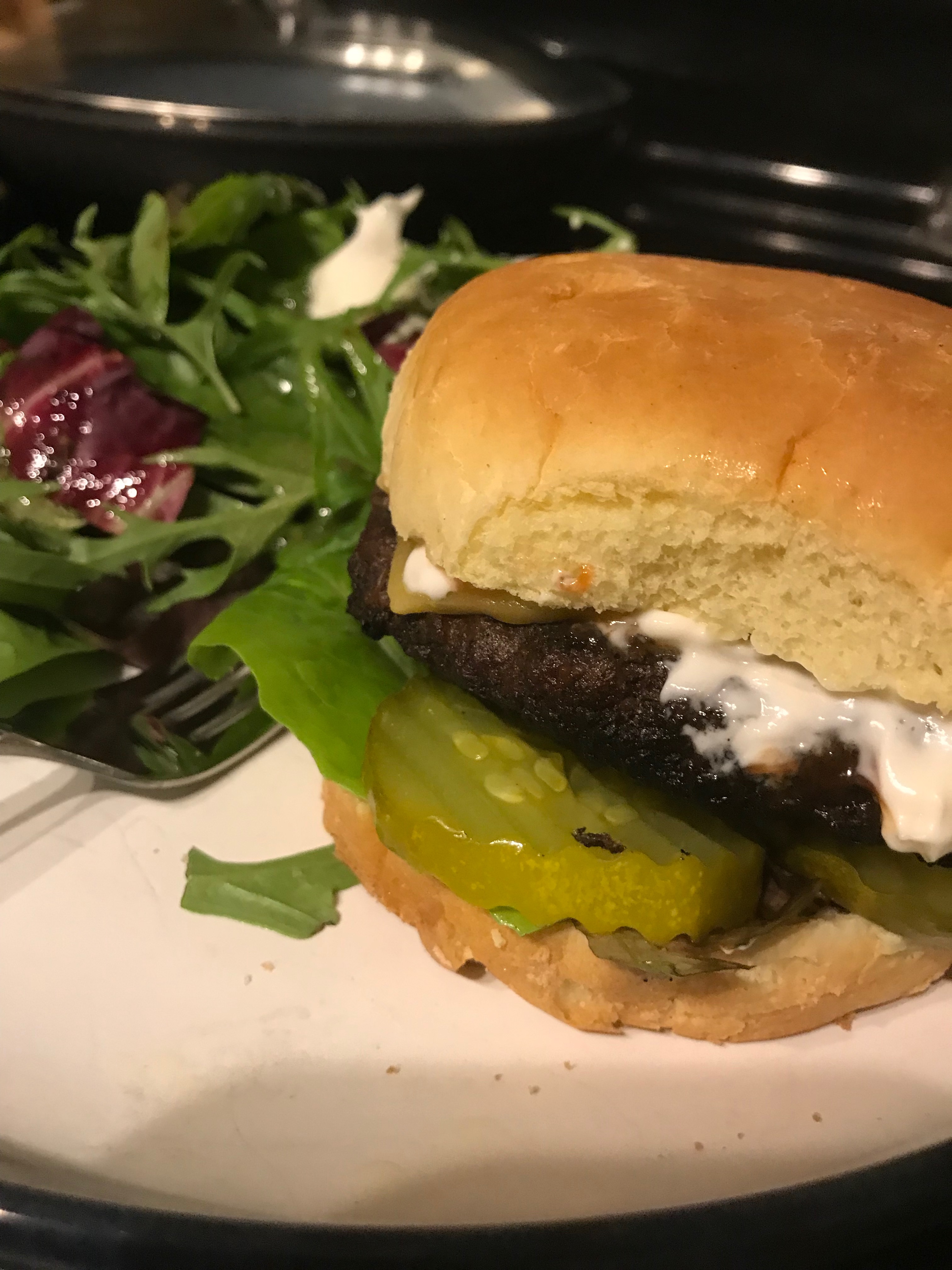 Hamburger with pickles cheese and mayo with a salad on the side