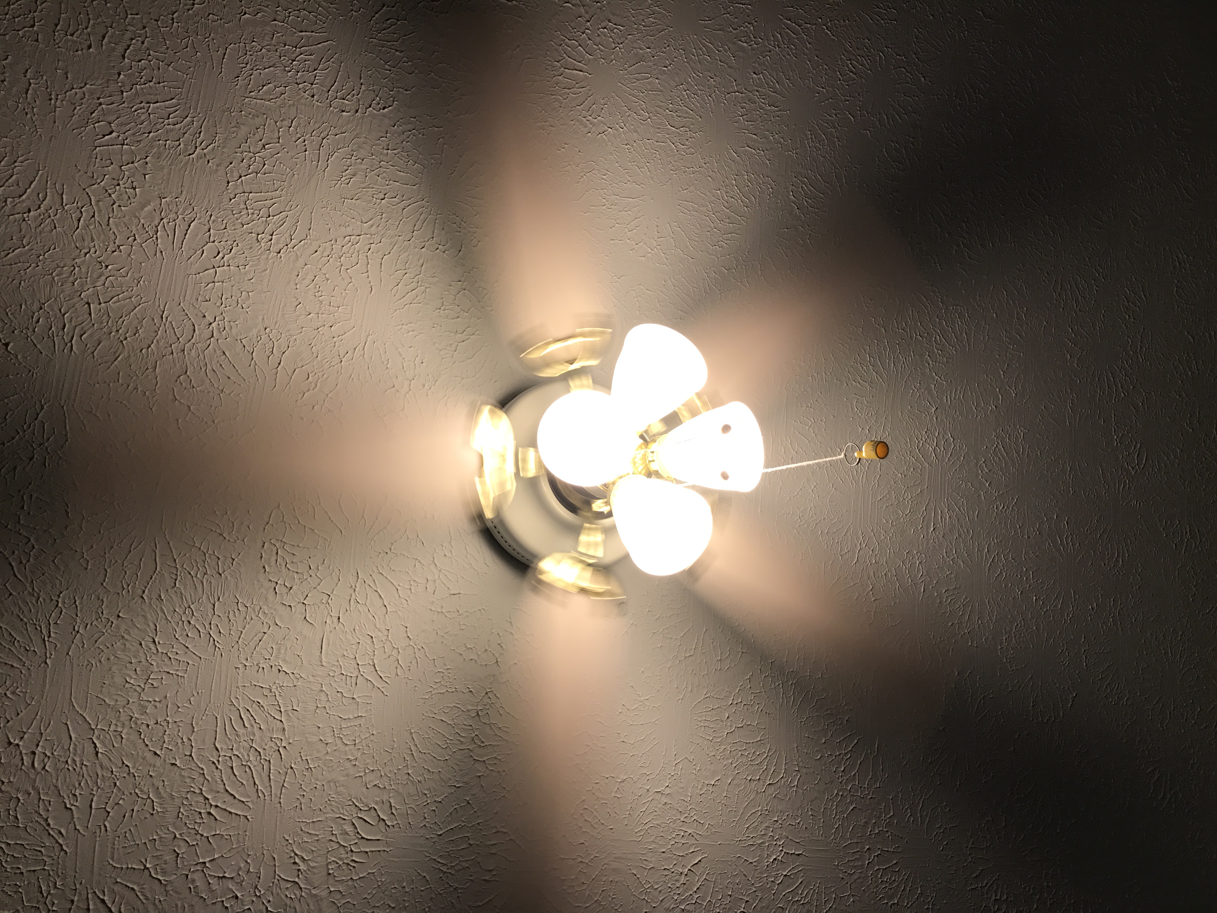 2 Photos of a ceiling fan, one with light on and one with light off.