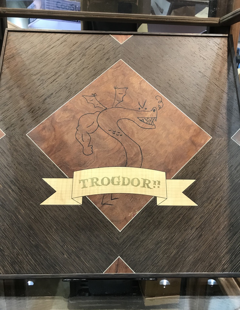 A square wooden game box with Trogdor a dragon with a big beefy human arm etched on the front