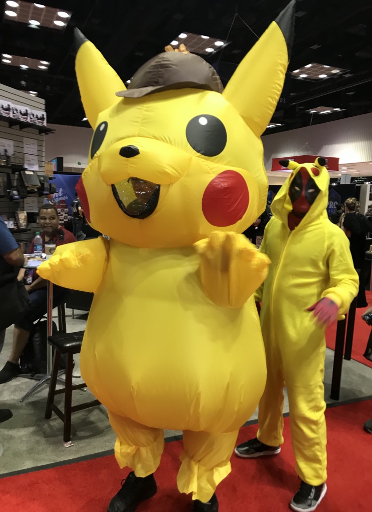A person in an inflatable pikachu costume followed by a person dressed as Deadpool wearing a Pikachu consume.