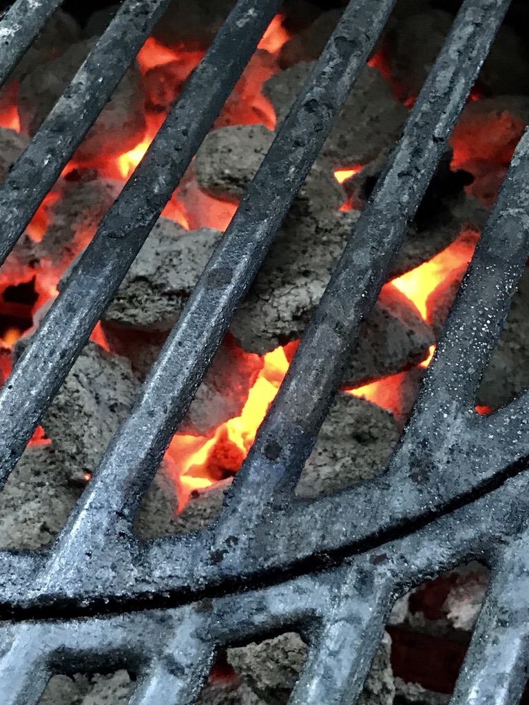 close up of a grill great with hot fire and charcoal beneath it.