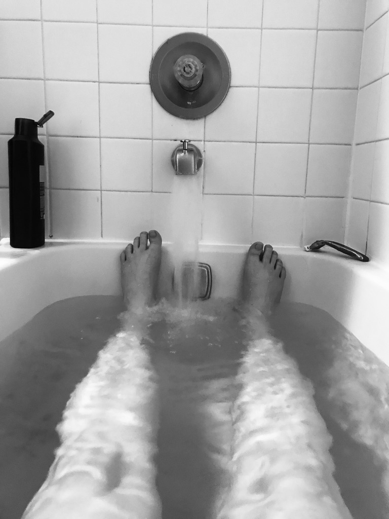 Legs an feet in a bathtub with water running. 