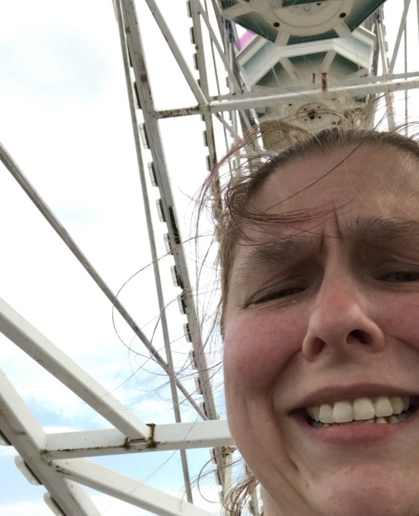 Pained face trying to smile with Farris wheel bars in background.