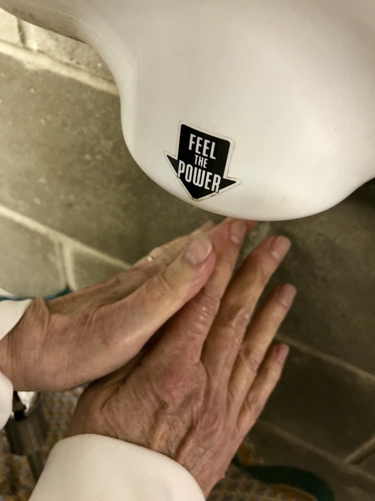wet hands drying under an automatic hand dryer.
