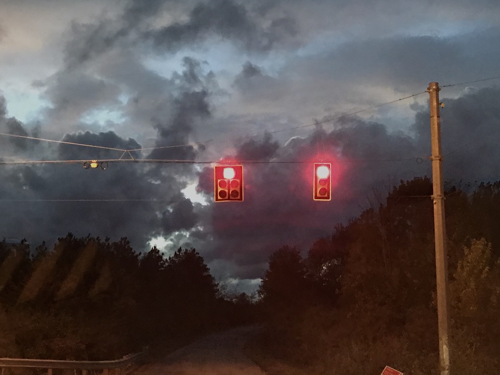 Red traffic lights with stormy clouds in background.