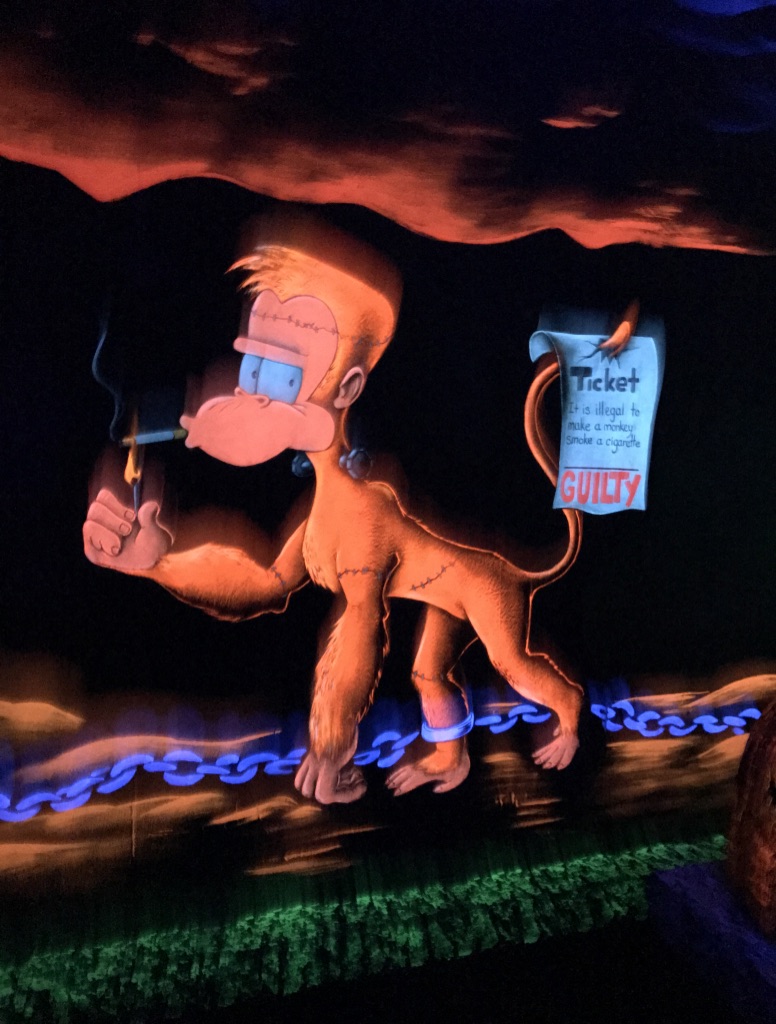 A wall painting of an orange neon black light monkey smoking a cigarette. 