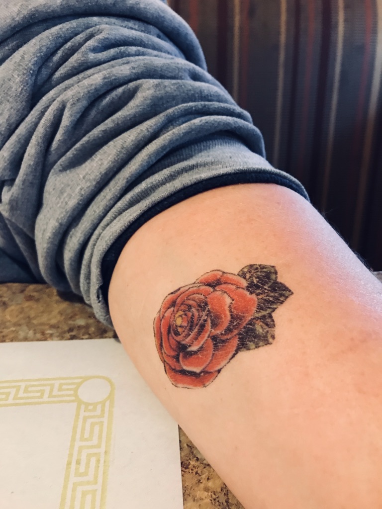 An arm with a temporary tattoo of a rose on it