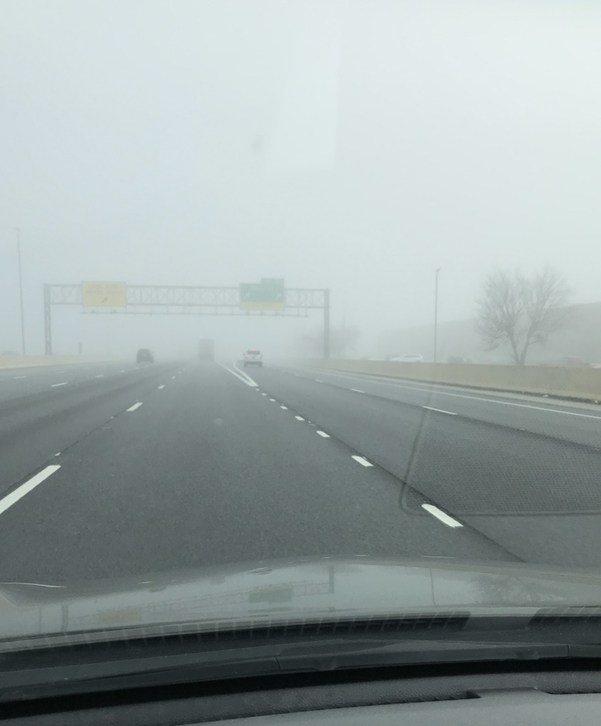 Foggy highway with cars and roadsign